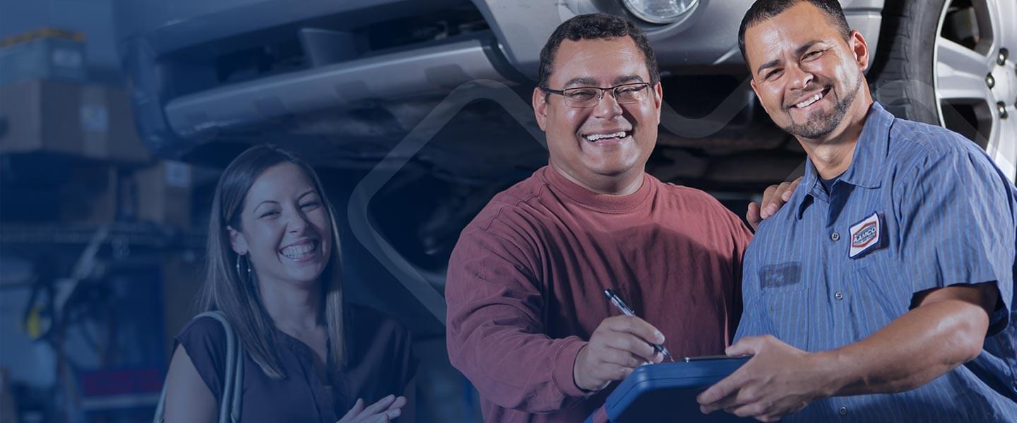 aamco car technician getting paper work signed by happy couple