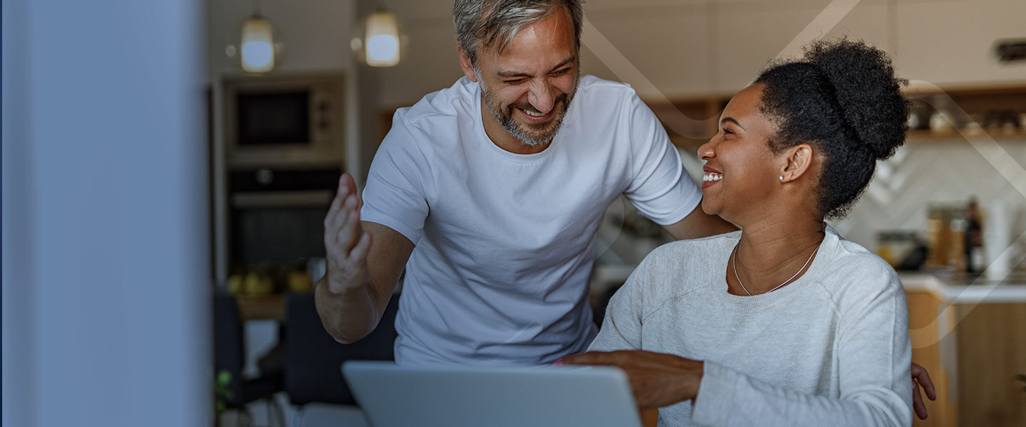 couple happily high fiving in front of computer