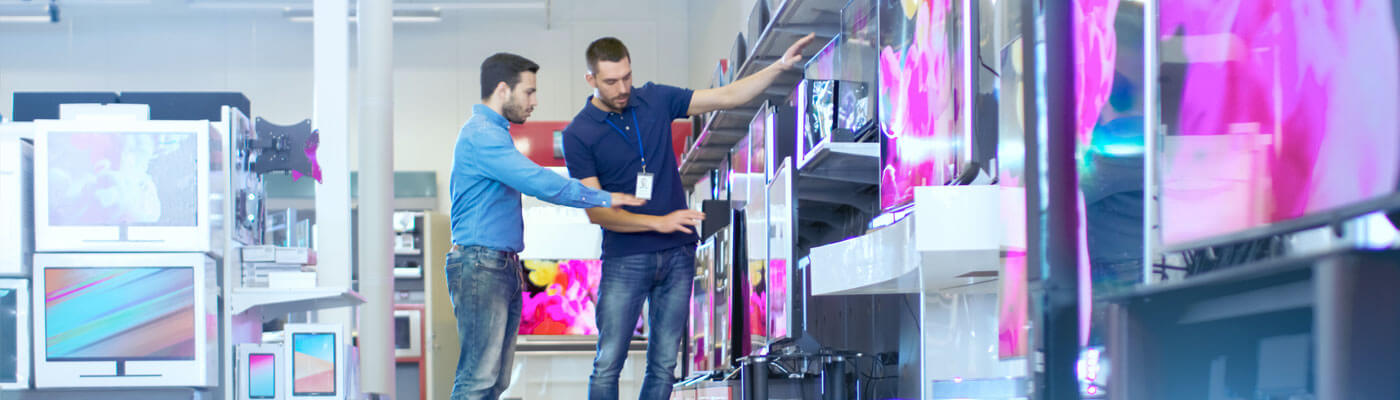 man talking to store associate about tvs in electronics store