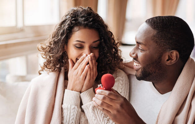 man surprising woman with engagement ring