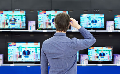 man looking quizzically at tv display in electronics store