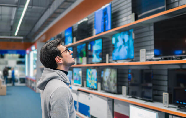 man looking at tvs in electronics store