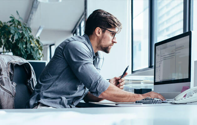 man looking closely at desktop computer in office