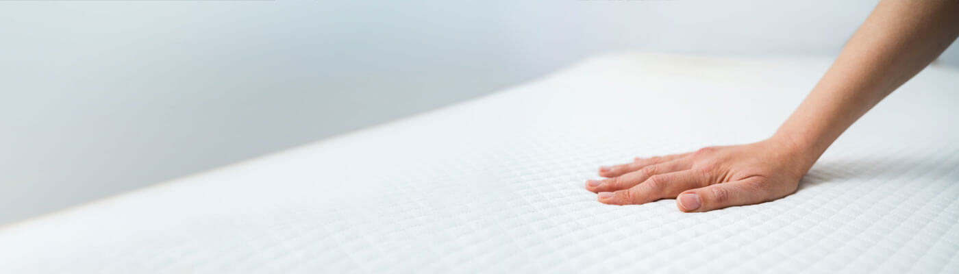 hand pushing into cushy mattress