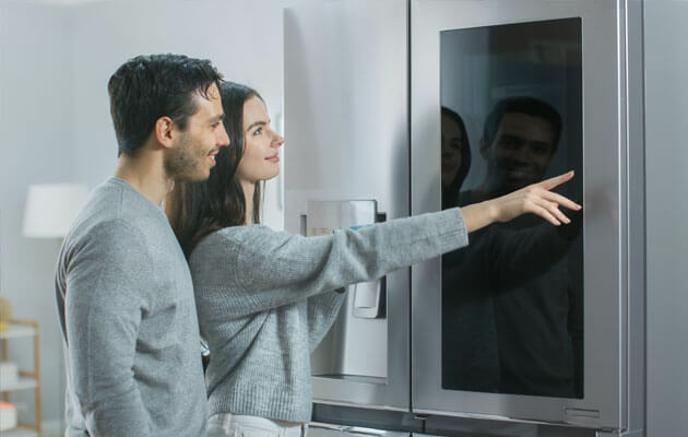 couple looking at smart fridge with touchscreen