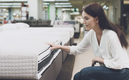 woman examining mattress in store