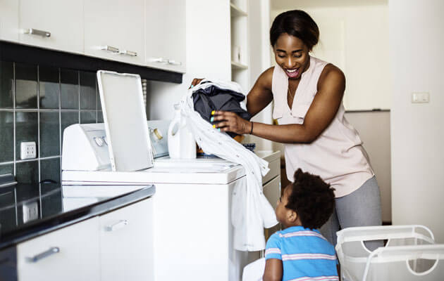 woman and son loading washer with clothes