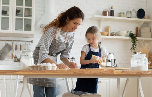 mother and daughter making pasta on kitchen table