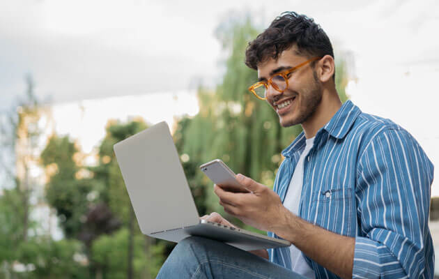 man glasses phone laptop smiling