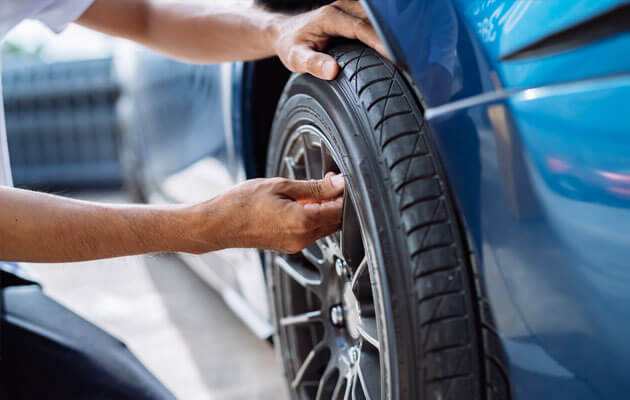 mechanic checking tire on car