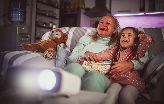 Grandma and grandkid watching tv projector