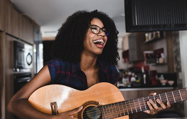 young woman playing guitar and laughing