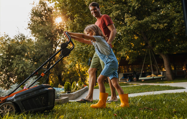 father daughter using push mower on yard