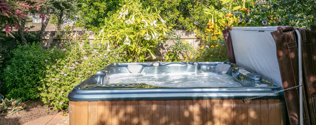 hot tub with cover in lush backyard