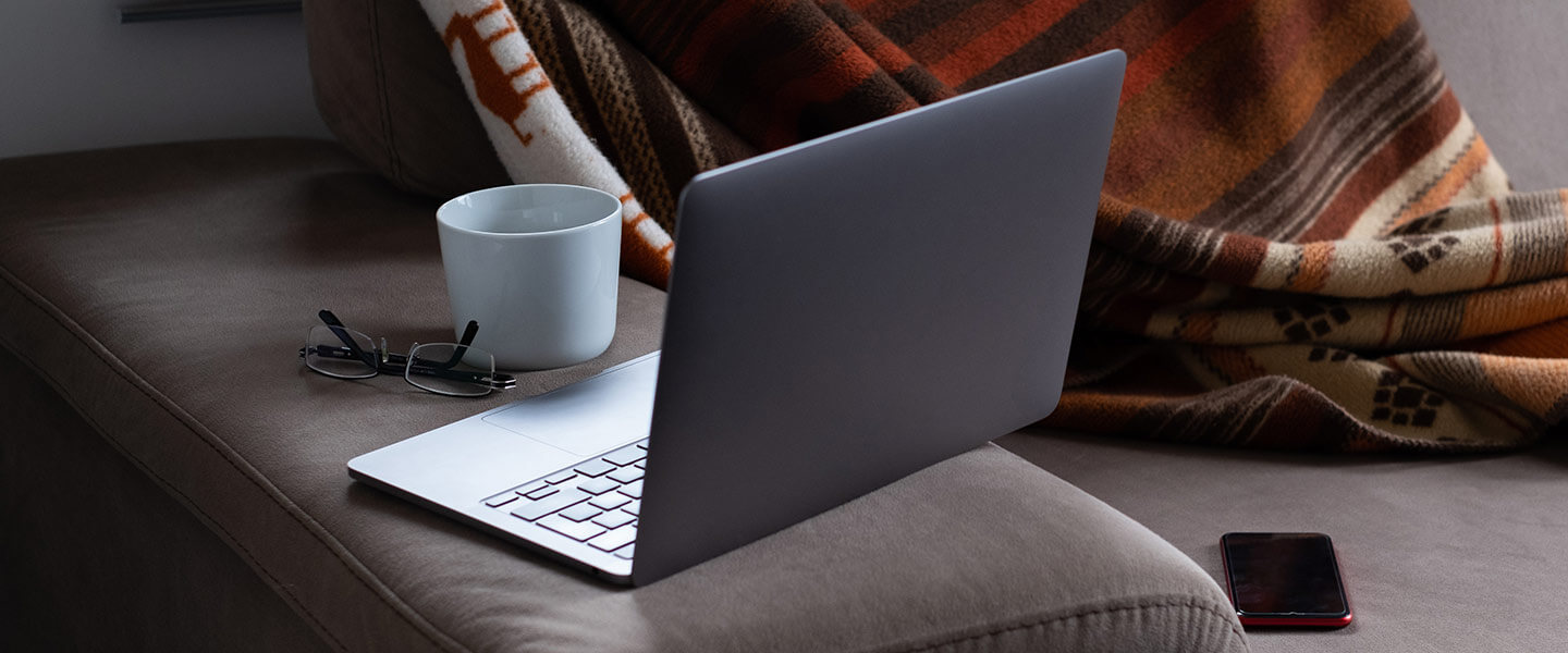 laptop on couch with coffee and blanket