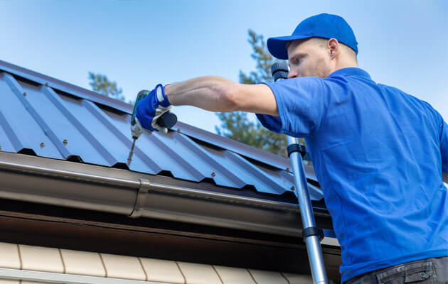 man installing metal roof on ladder