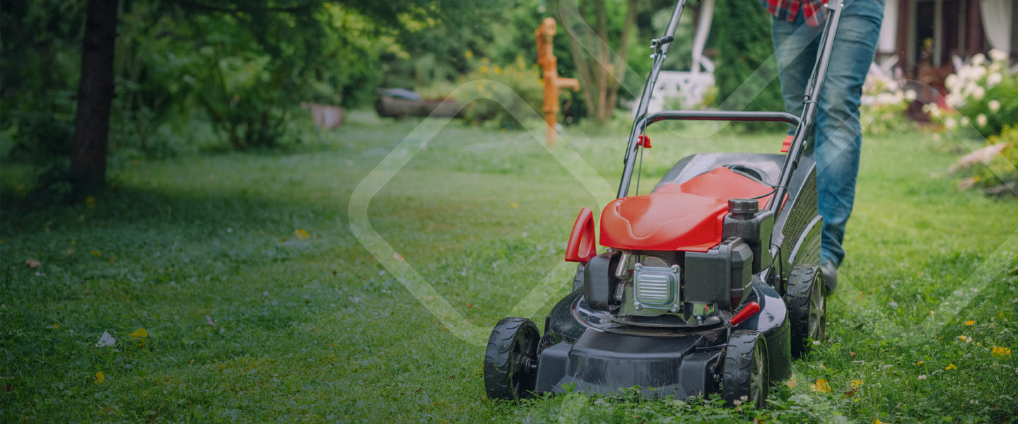 man pushing lawn mower across yard