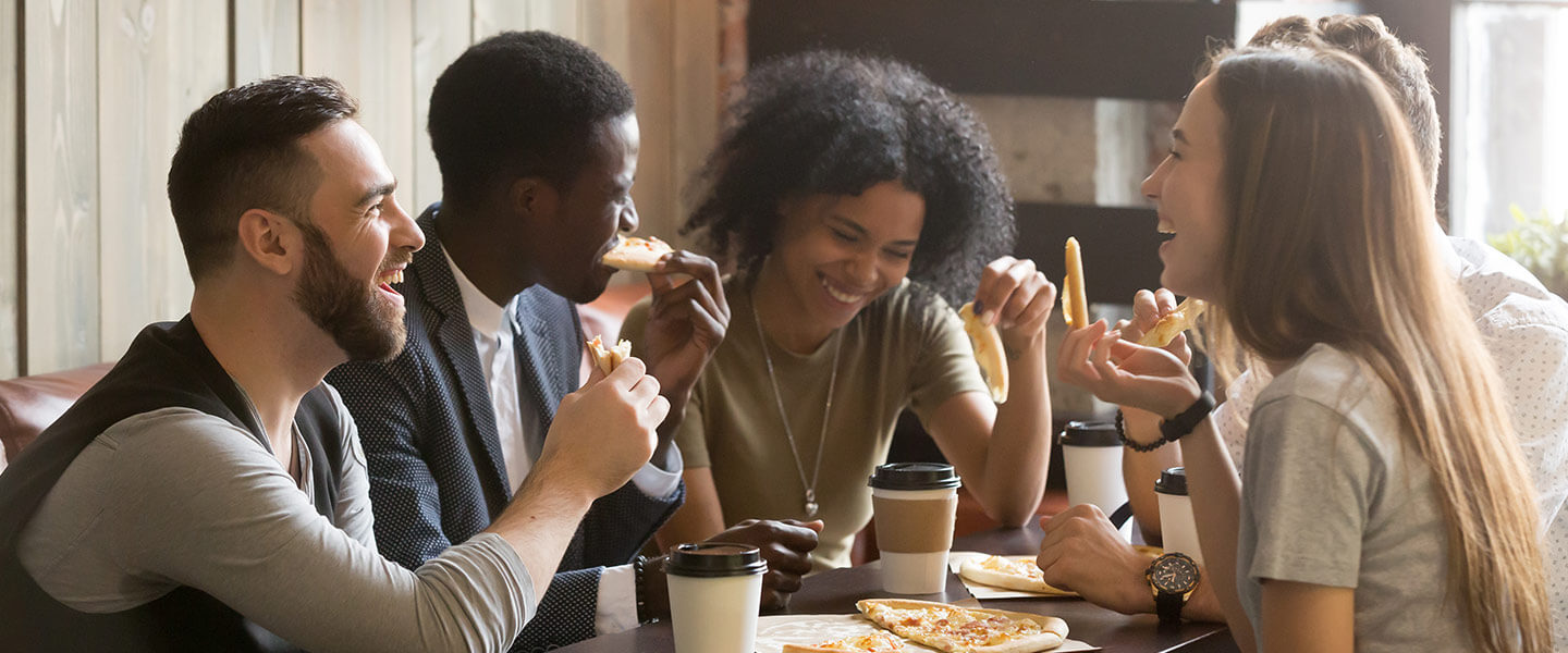 Friends laughing and eating pizza.