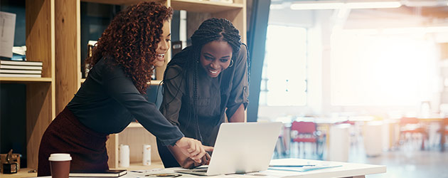 Two businesswomen discussing something on a laptop at the office