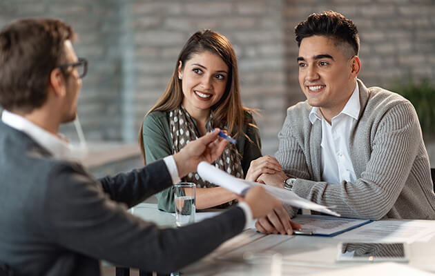 Happy couple having a meeting with bank manager who is offering them a contract to sign