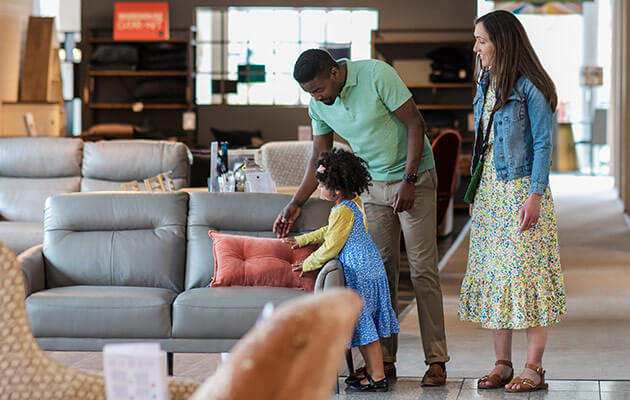 family of three looking at new sofas in a department store