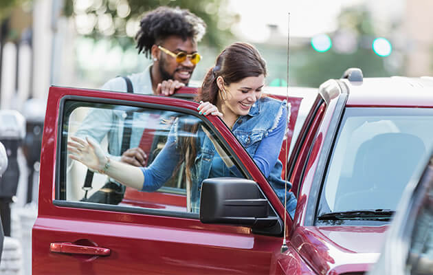 Multi-ethnic young adults getting in parked car.