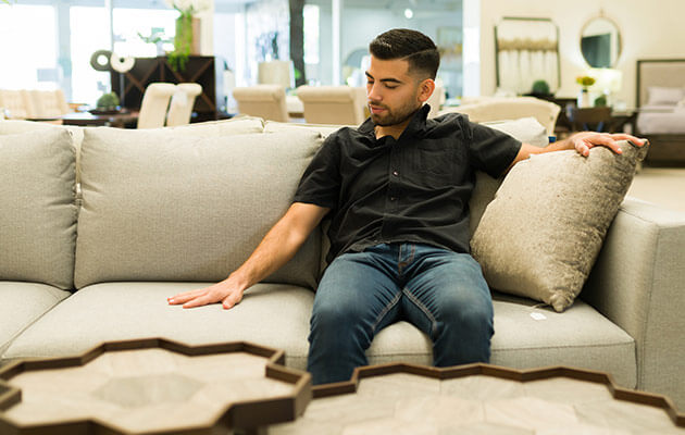 young man sitting on a beautiful new couch at the furniture store