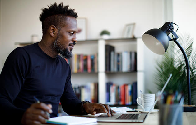 Smiling man at home working on laptop.