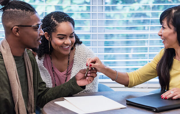 Young couple meeting with Real Estate Agent, handing over key.