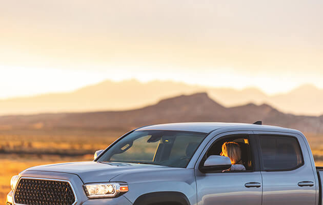 Woman in pickup truck enjoying scenic sunrise.