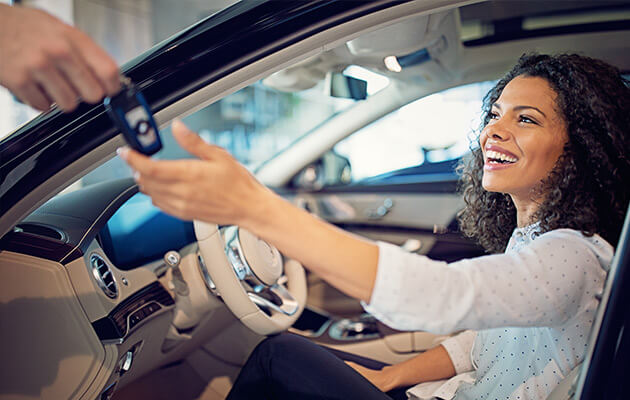 Car dealer is giving key for a new car to a woman