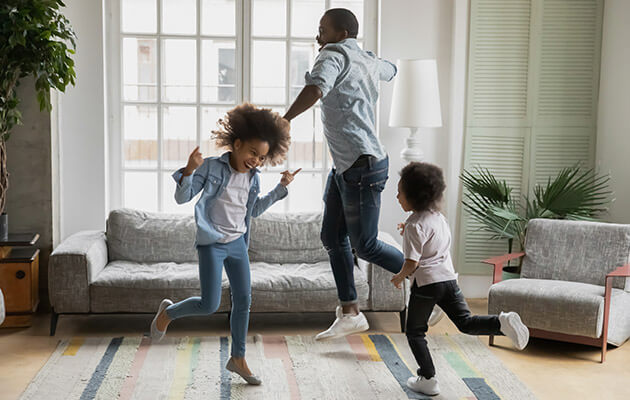 happy dad and kids laughing and dancing around living room