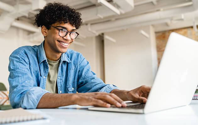 young man smiling and typing on laptop