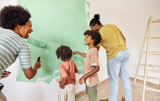 happy family laughing and painting the wall together