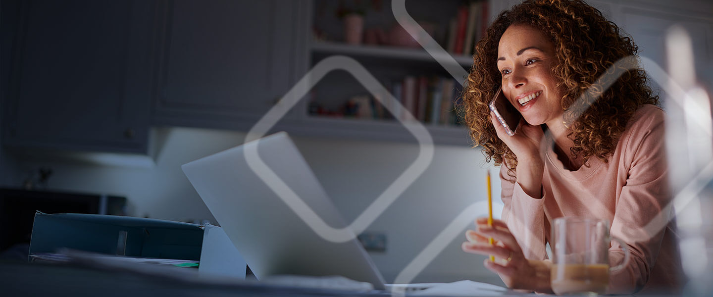 Woman talking on phone while looking at laptop