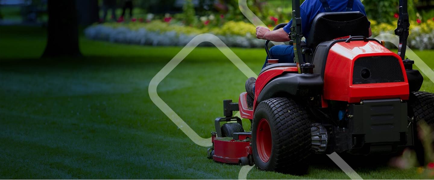 man riding red lawnmower through green grass