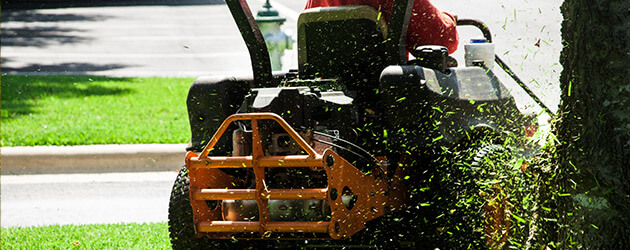 person riding lawnmower cutting grass