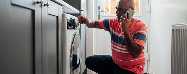 men looking at washer and talking on the phone